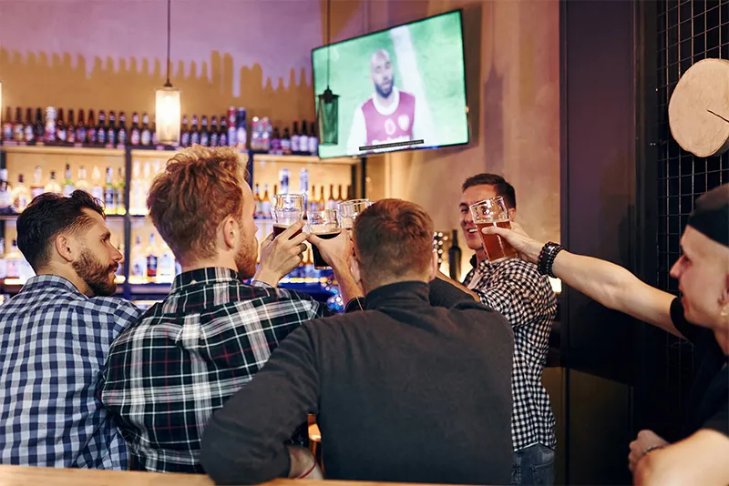 TV playing with closed captions visible at a busy bar.