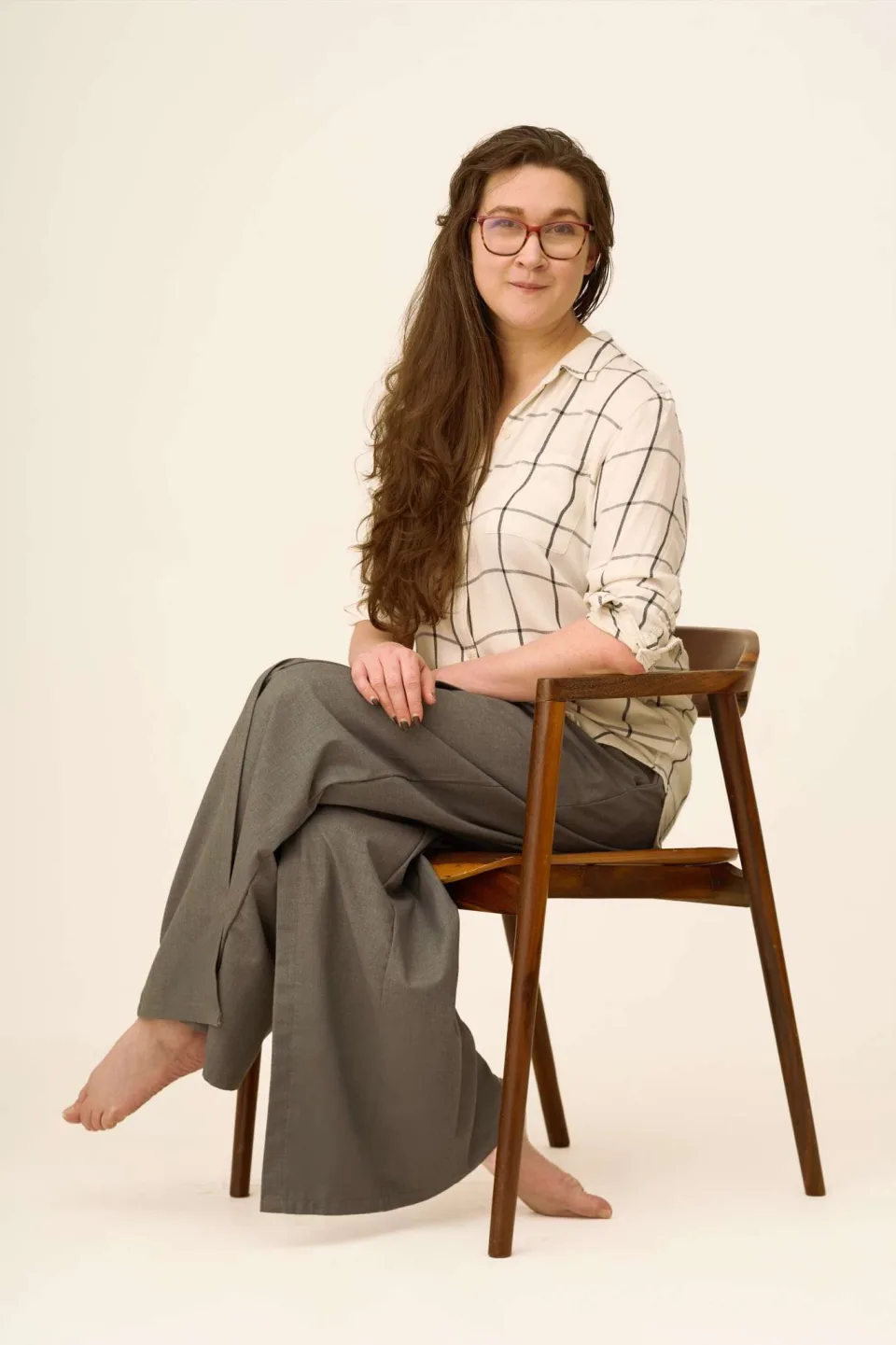 Malak Janus, seated in a wooden chair, smiling